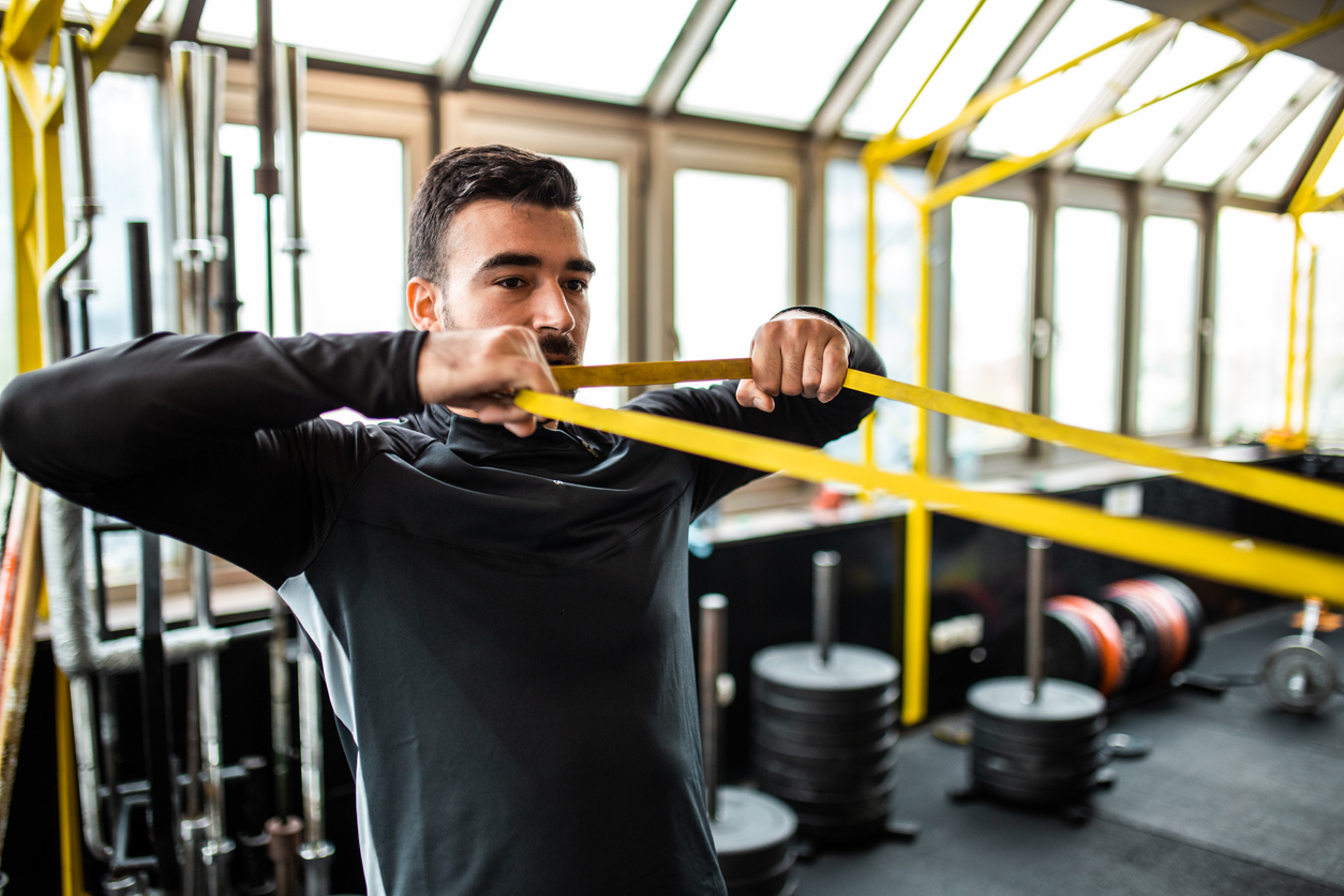 man stretching his shoulder with an elastic band