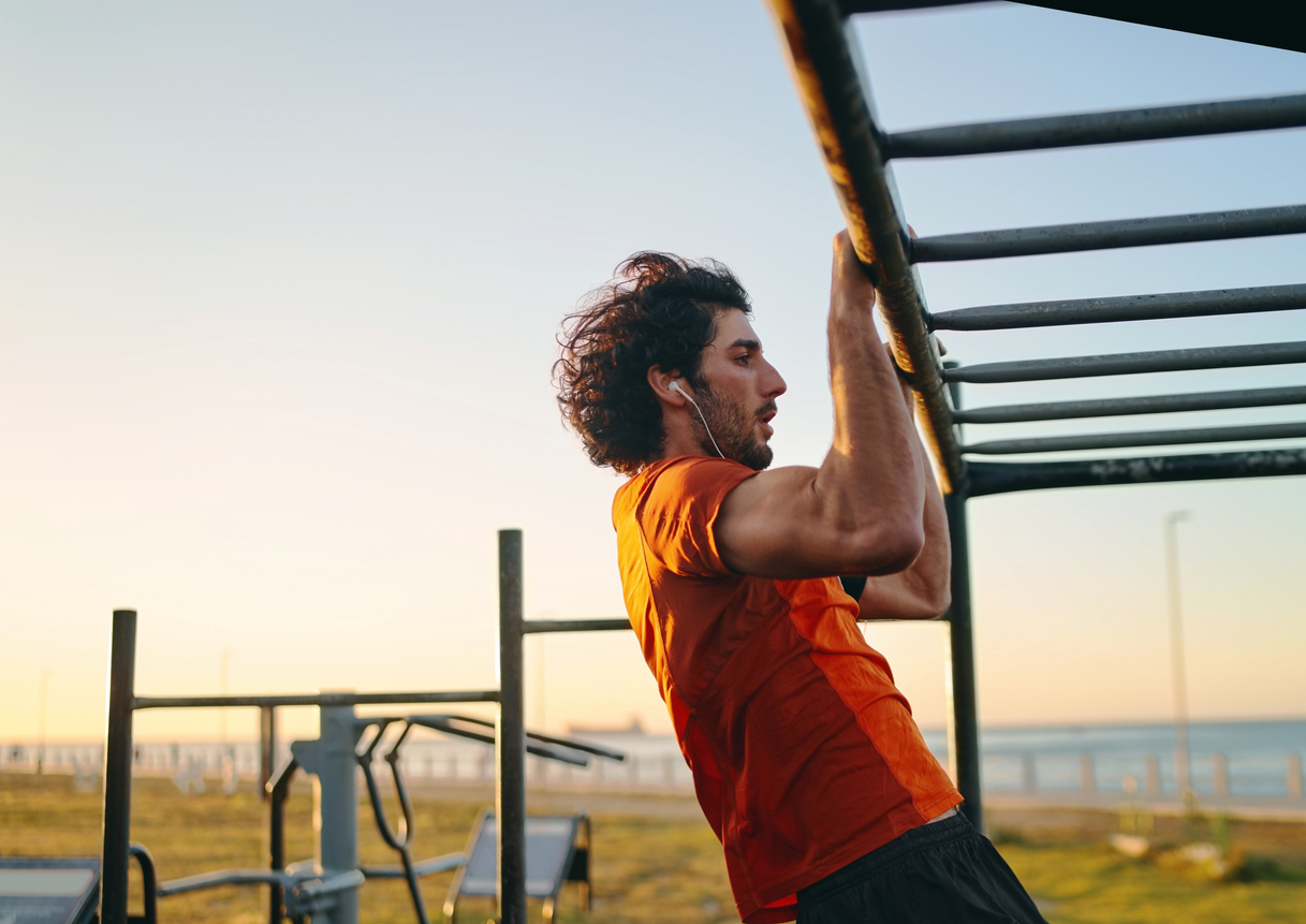 man doing pull ups outside