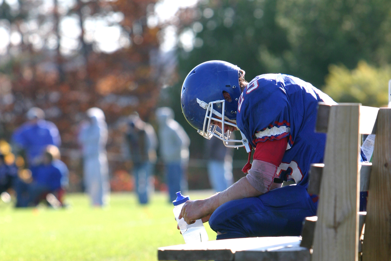 student athlete sitting on bench during football game